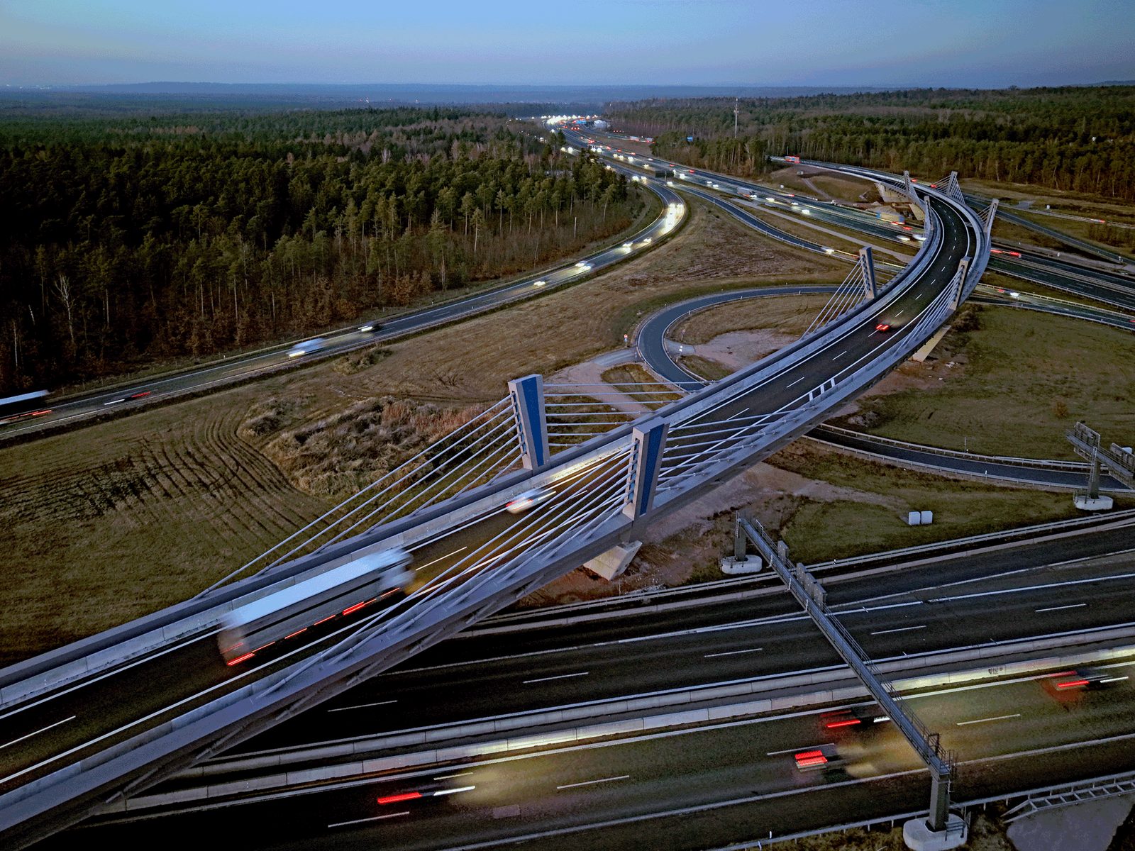 Luftbild des Autobahnkreuzes in der Dämmerung mit Lichtspuren des Verkehrs
