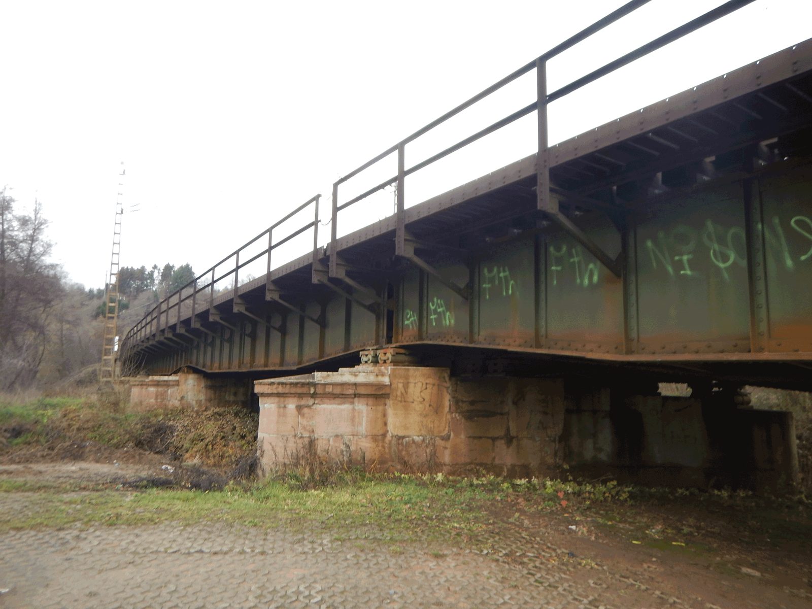 Stahlträger einer Eisenbahnbrücke auf massiven Pfeilern, von unten gesehen