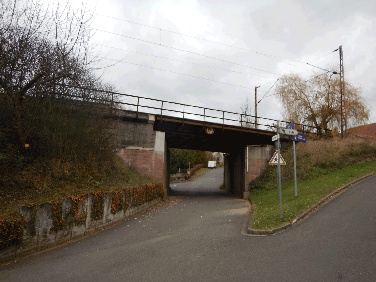 Schmale Straße unter einer Eisenbahnbrücke mit geradem Stahlüberbau