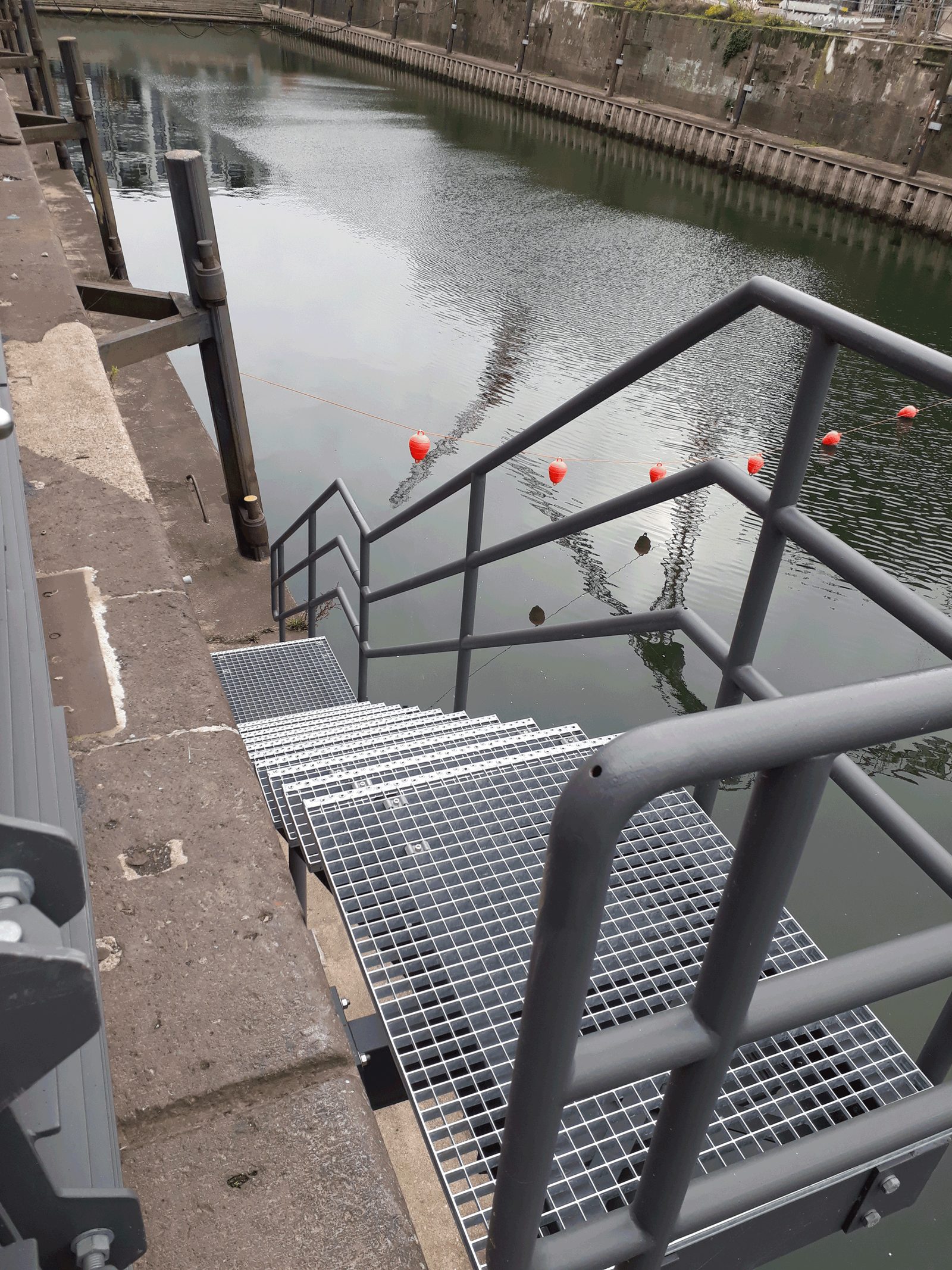 Neue Gitterroststeg-Anlage mit Geländer an der Kaimauer über dem Wasser