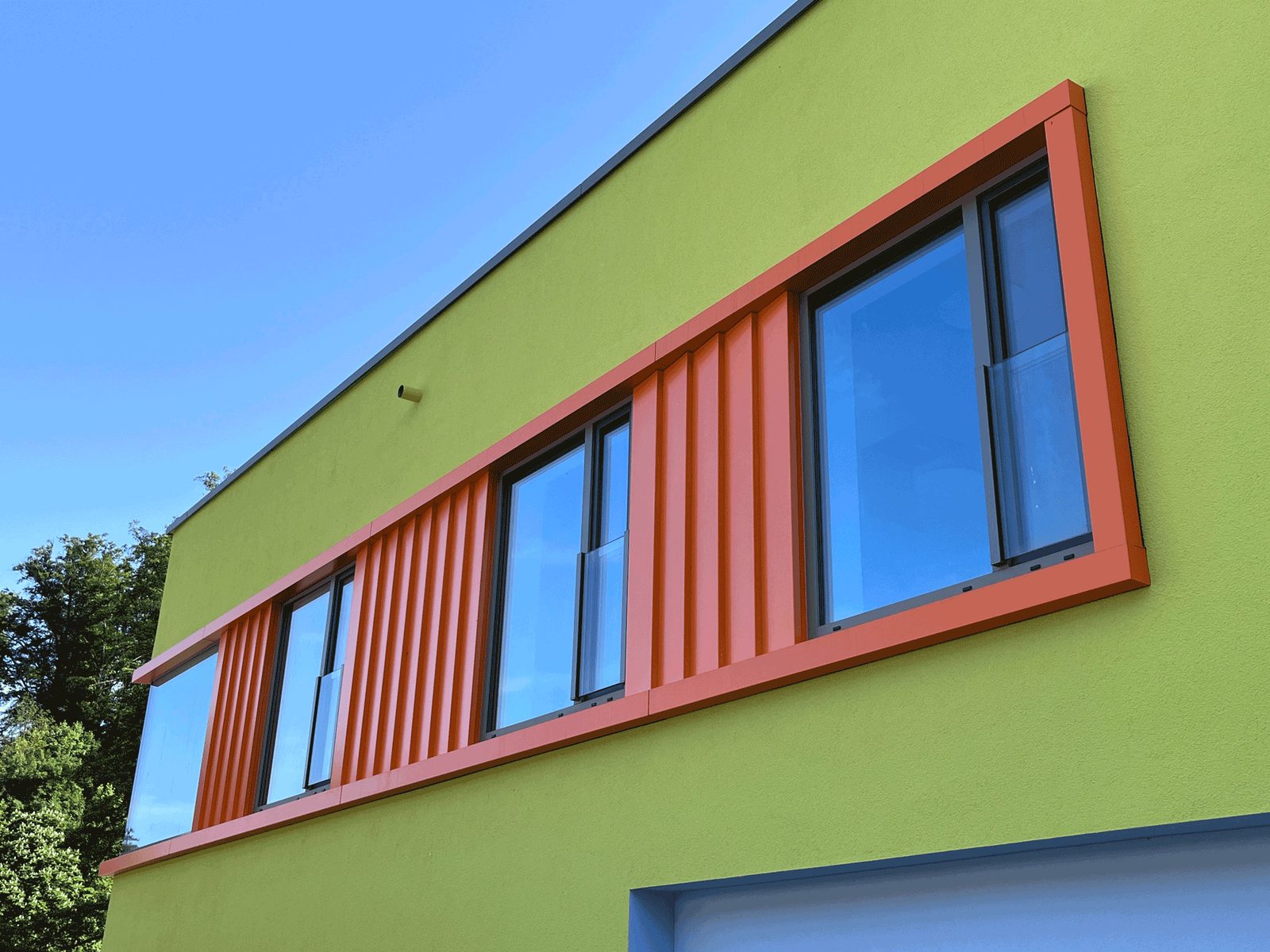 Grüne Fassade des Kindergartens Neckarsteinach mit orange gerahmtem Fensterband