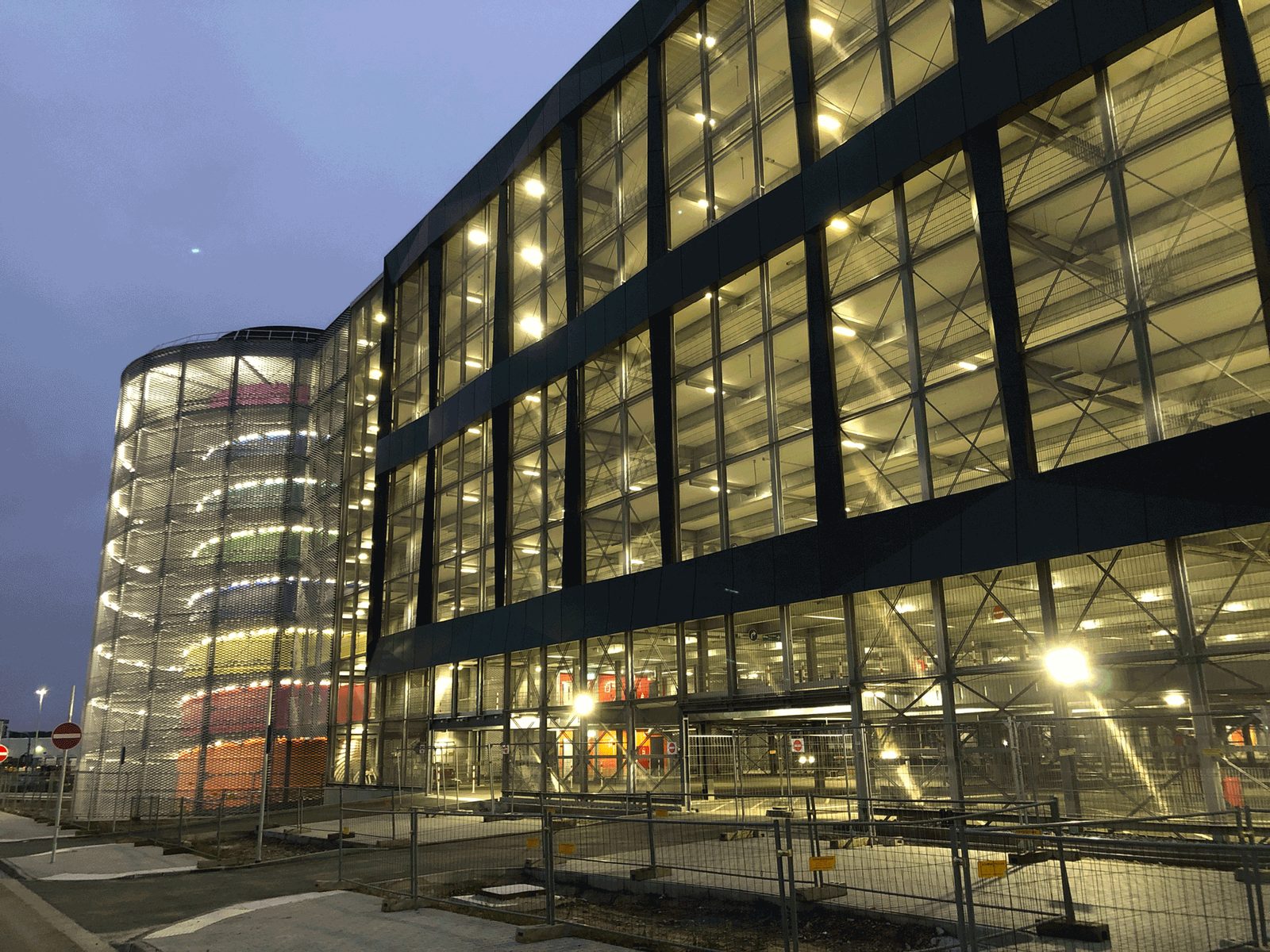 Beleuchtete Fassade des Parkhauses Terminal 3 mit rundem Rampenturm