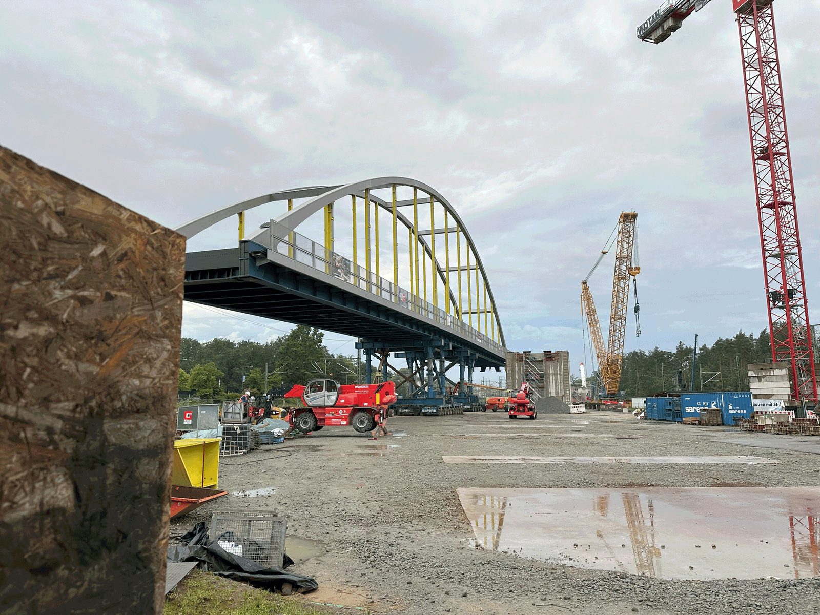 Stabbogenbrücke auf dem Montageplatz, daneben ein Raupenkran