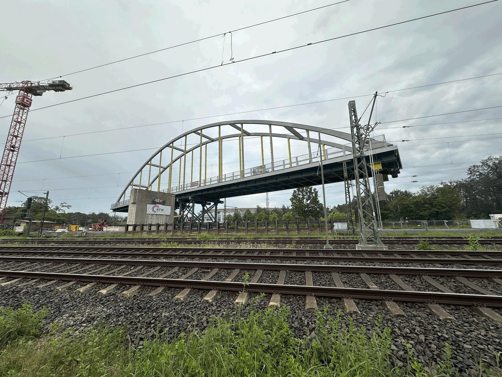 Die Stabbogenbrücke über den Gleisanlagen, im Vordergrund Schienen