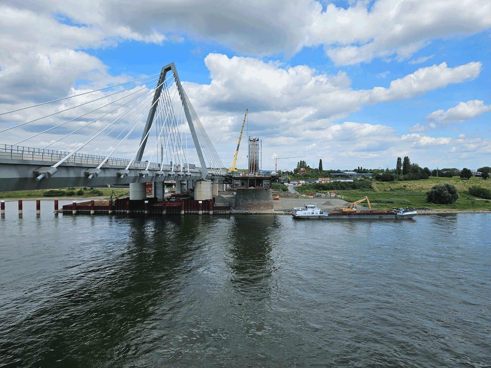 Die Rheinbrücke Leverkusen vom Ufer aus, davor ein Frachtschiff