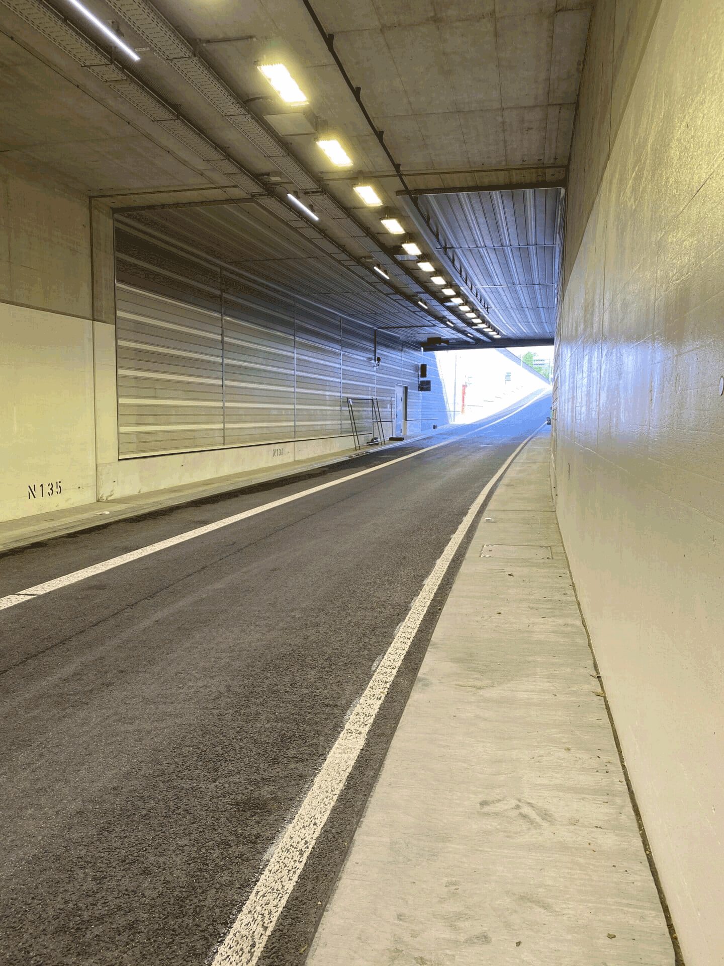 Fahrbahn im Tunnel Kriegsstraße mit heller Wandverkleidung, Blick zur Ausfahrt
