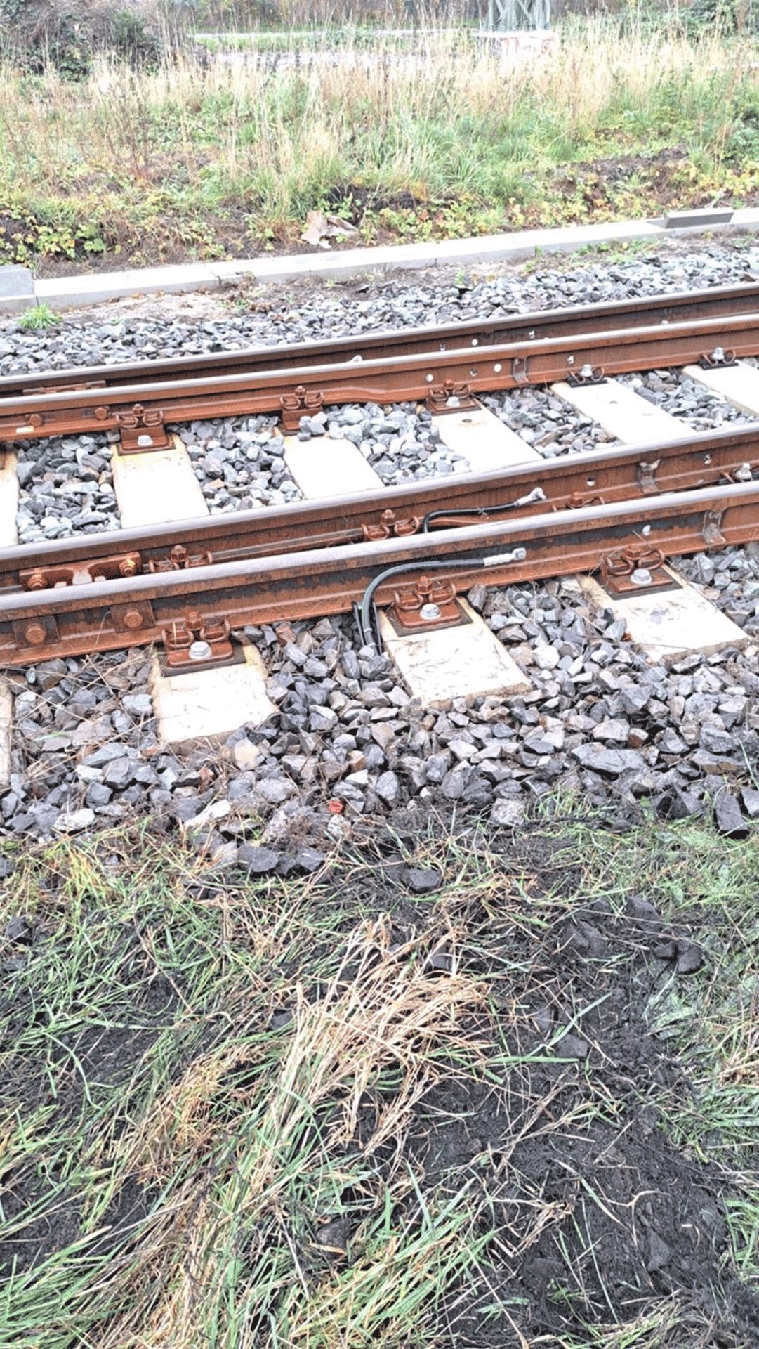 Im Gleis verlegte Kabel für die Weichenheizung zwischen den Schwellen